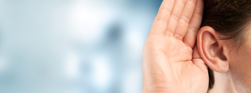 Eine Person hält ihre Hand hinter das Ohr, als ob sie lauschen würde.