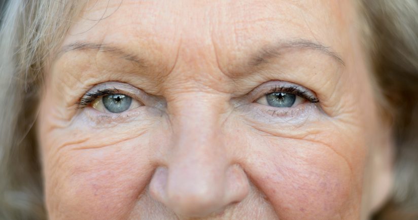 Nahaufnahme eines älteren Gesichts mit Falten und grauen Haaren.