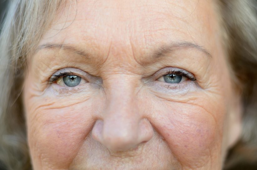 Nahaufnahme eines älteren Gesichts mit Falten und grauen Haaren.